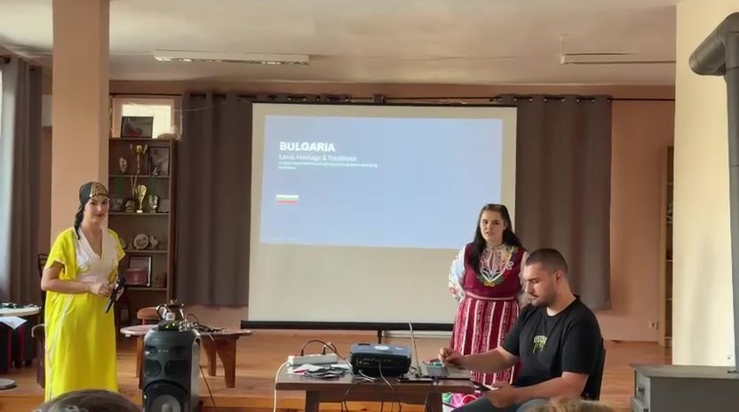 Участници пред екран с презентация за България в читалището.